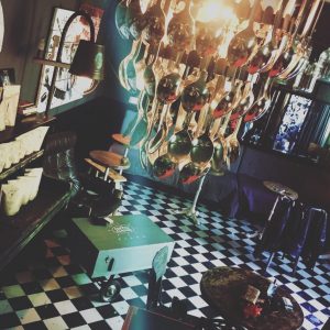 Coffee Circus Piano Vilnius interior with vintage checkered floor, eclectic turquoise dÃ©cor, artistic wall projections, and intimate cafÃ© seating