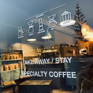 Specialty coffee shop window with brewing methods illustrations and signage