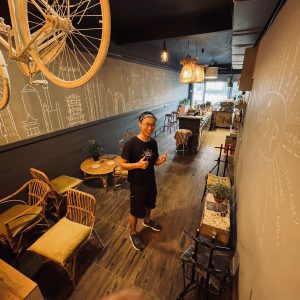 Barista at Coffee Circus cafe interior with bicycle wall art